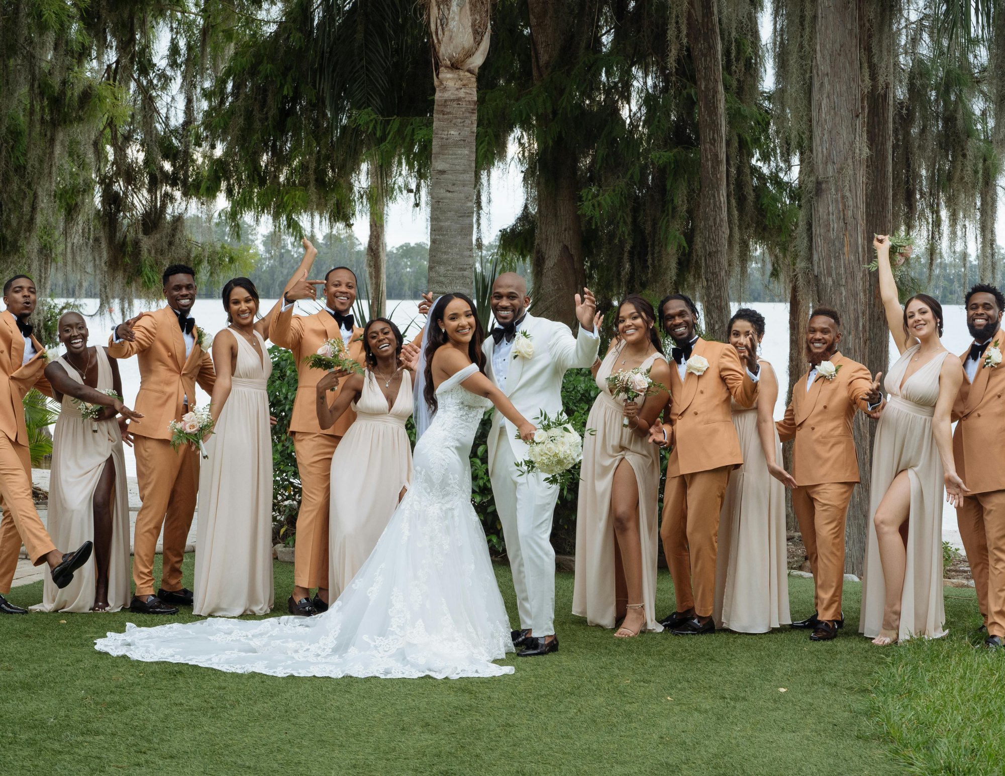 Bride and groom posing playfully with their bridesmaids and groomsmen during a group photo session.