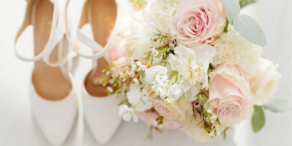 Préparatifs de mariage élégants avec chaussures de mariée blanches et bouquet romantique de roses pâles et fleurs blanches - accessoires essentiels pour un mariage dans les Caraïbes