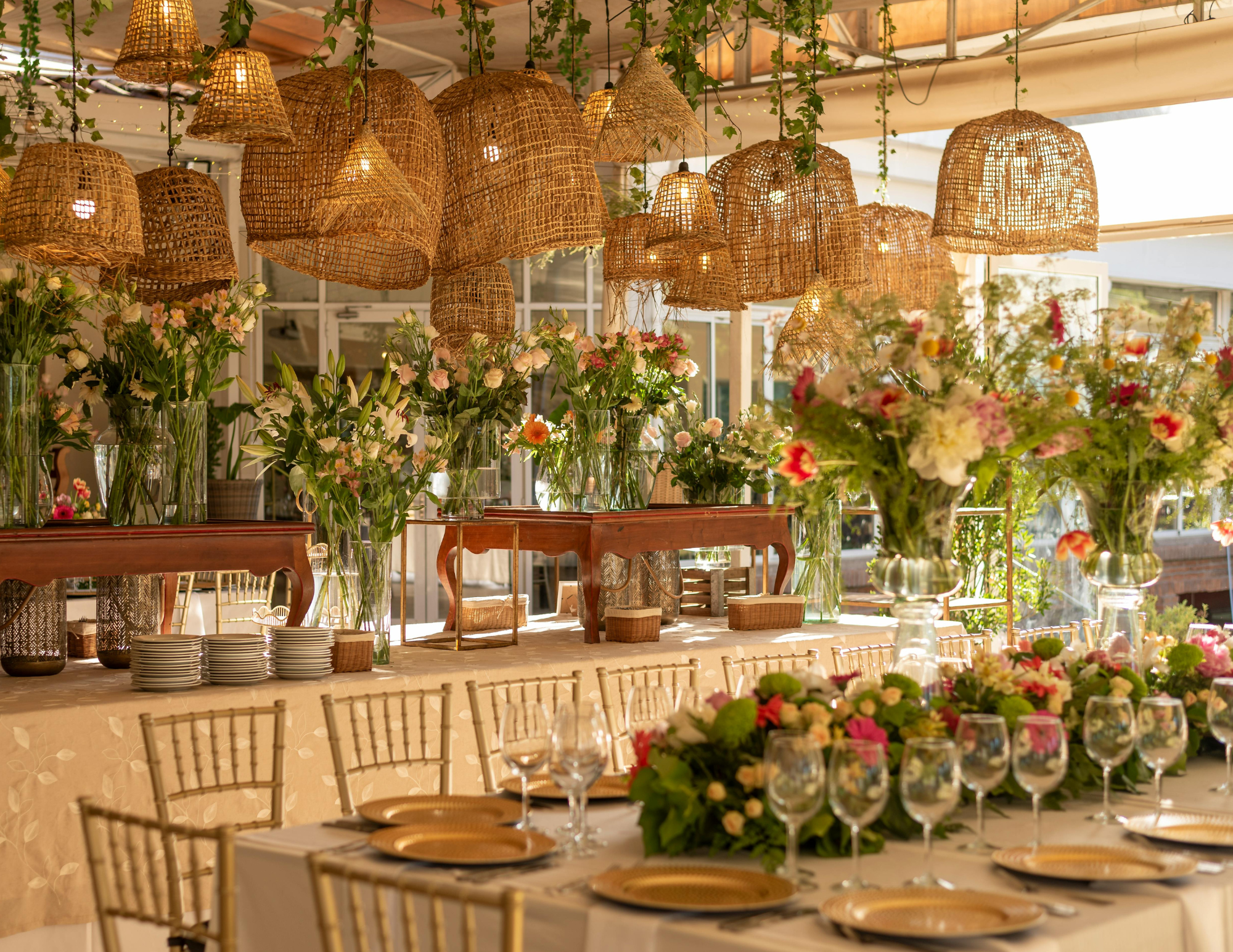 Tropical wedding decoration with wicker pendant lights, colorful floral arrangements and dressed tables for Caribbean reception