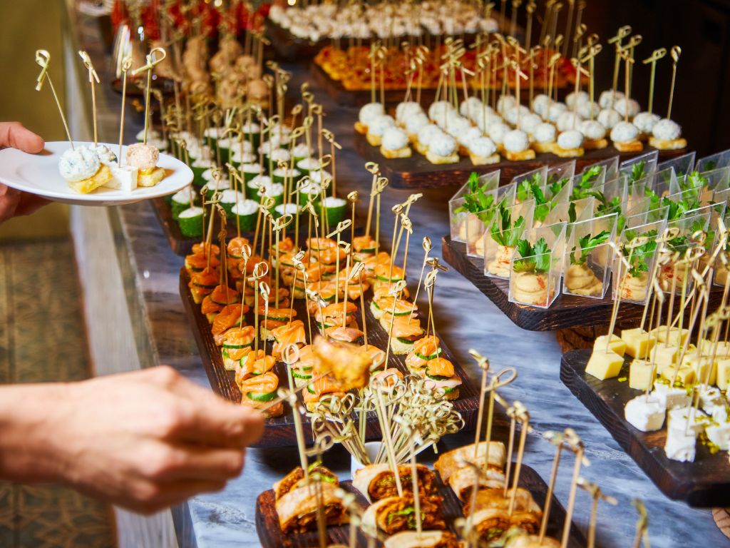 Buffet gourmand de cocktail pour vin d'honneur de mariage aux Caraïbes avec sélection raffinée de canapés et bouchées sur présentoirs élégants
