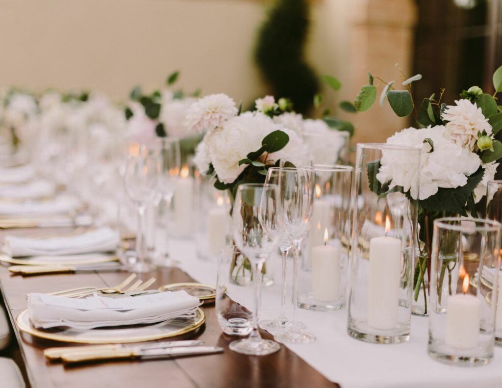Table de mariage décorée avec élégance dans un style minimaliste, ornée de fleurs blanches et bougies.