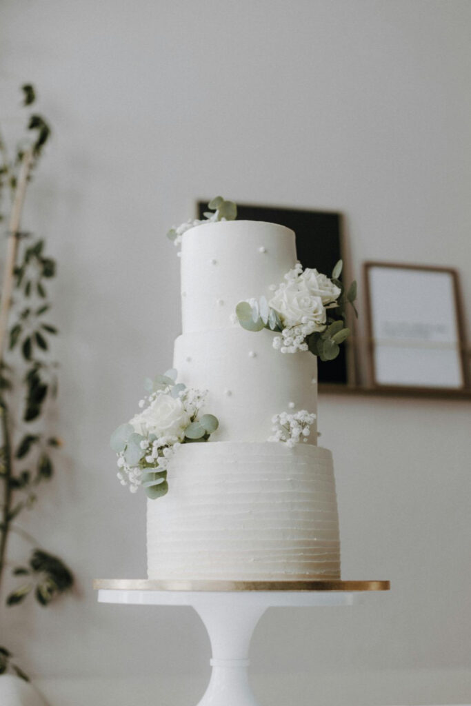 Pièce montée - un magnifique wedding cake blanc décoré avec quelques fleurs.